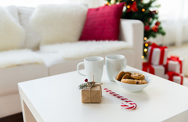 Image showing close up of gift, sweets and cups on table at home