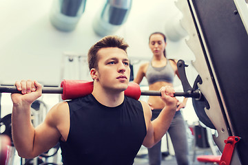 Image showing man and woman with barbell flexing muscles in gym