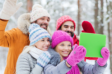 Image showing smiling friends with tablet pc in winter forest