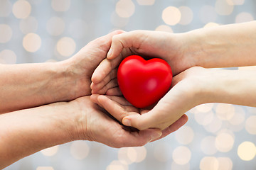 Image showing senior and young woman hands holding red heart