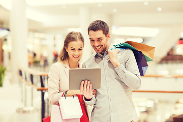 Image showing couple with tablet pc and shopping bags in mall