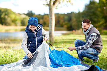Image showing happy father and son setting up tent outdoors