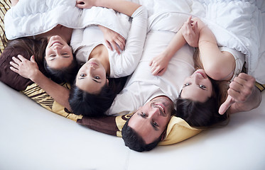 Image showing handsome man in bed with three beautiful woman