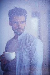 Image showing relaxed young man drink first morning coffee withh rain drops on