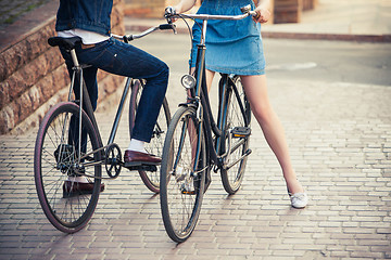 Image showing Young couple sitting on a bicycle opposite the city 