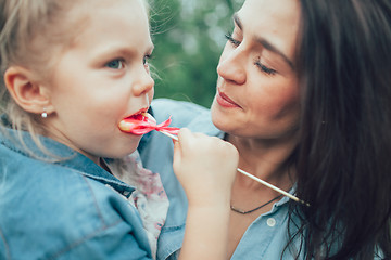 Image showing The young mother and daughter on green grass background 