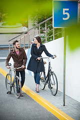 Image showing Young couple with a bicycle opposite city 