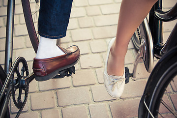 Image showing Young couple sitting on a bicycle opposite the city 