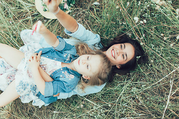 Image showing The young mother and daughter on green grass background 