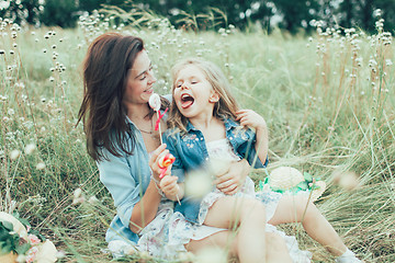 Image showing The young mother and daughter on green grass background 