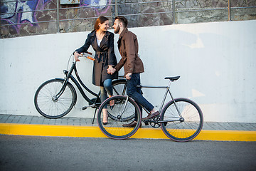 Image showing Young couple with a bicycle opposite city 