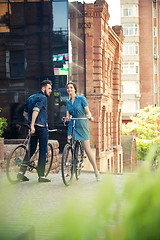 Image showing Young couple sitting on a bicycle opposite the city 