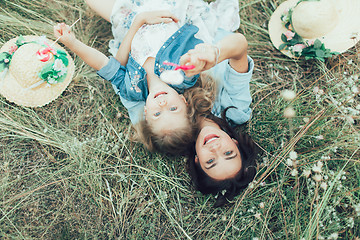 Image showing The young mother and daughter on green grass background 