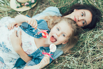 Image showing The young mother and daughter on green grass background 