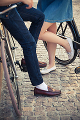 Image showing Young couple sitting on a bicycle opposite the city 