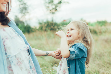 Image showing The young mother and daughter on green grass background 