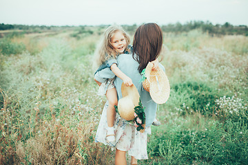 Image showing The young mother and daughter on green grass background 