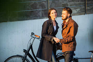 Image showing Young couple with a bicycle opposite city 