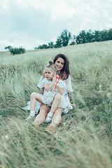 Image showing The young mother and daughter on green grass background 