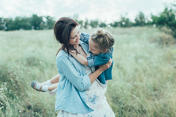 Image showing The young mother and daughter on green grass background 