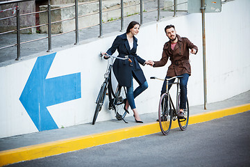 Image showing Young couple with a bicycle opposite city 