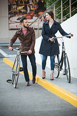 Image showing Young couple with a bicycle opposite city 