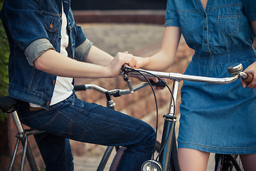 Image showing Young couple sitting on a bicycle opposite the city 