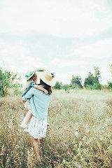 Image showing The young mother and daughter on green grass background 