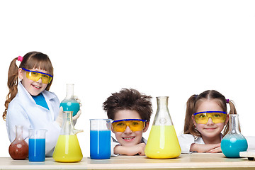 Image showing The three cute children at chemistry lesson making experiments on white background
