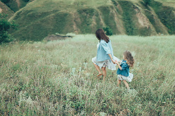 Image showing The young mother and daughter on green grass background 