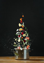 Image showing Fresh vegetables falling into a stainless steel casserole 