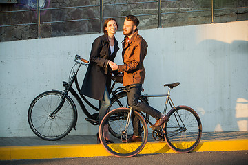 Image showing Young couple with a bicycle opposite city 