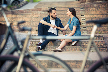 Image showing Young couple sitting opposite  a bicycle 