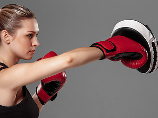 Image showing beautiful woman is boxing on gray background