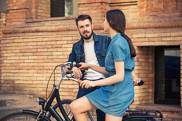 Image showing Young couple sitting on a bicycle opposite city 