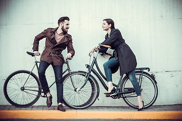 Image showing Young couple with a bicycle opposite city 