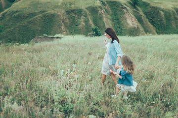 Image showing The young mother and daughter on green grass background 