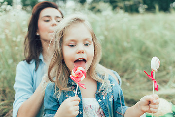 Image showing The young mother and daughter on green grass background 