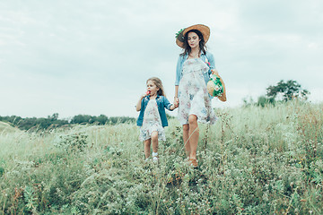 Image showing The young mother and daughter on green grass background 