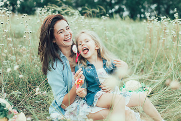 Image showing The young mother and daughter on green grass background 