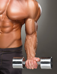 Image showing Closeup of a handsome power athletic man bodybuilder doing exercises with dumbbell 