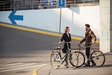 Image showing Young couple with a bicycle opposite city 