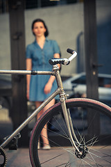 Image showing Young girl with a bicycle opposite city 