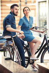 Image showing Young couple sitting on a bicycle opposite city 