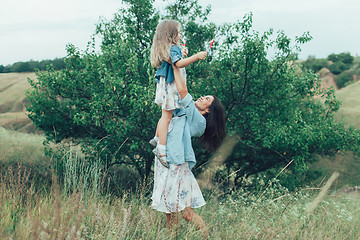 Image showing The young mother and daughter on green grass background 