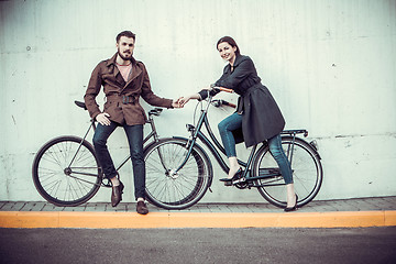 Image showing Young couple with a bicycle opposite city 