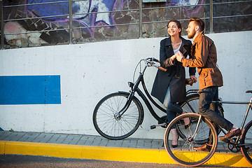 Image showing Young couple with a bicycle opposite city 