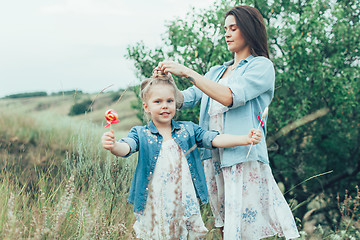 Image showing The young mother and daughter on green grass background 