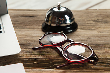 Image showing The laptop, blank paper, glasses and small bell on the wooden table 