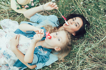 Image showing The young mother and daughter on green grass background 